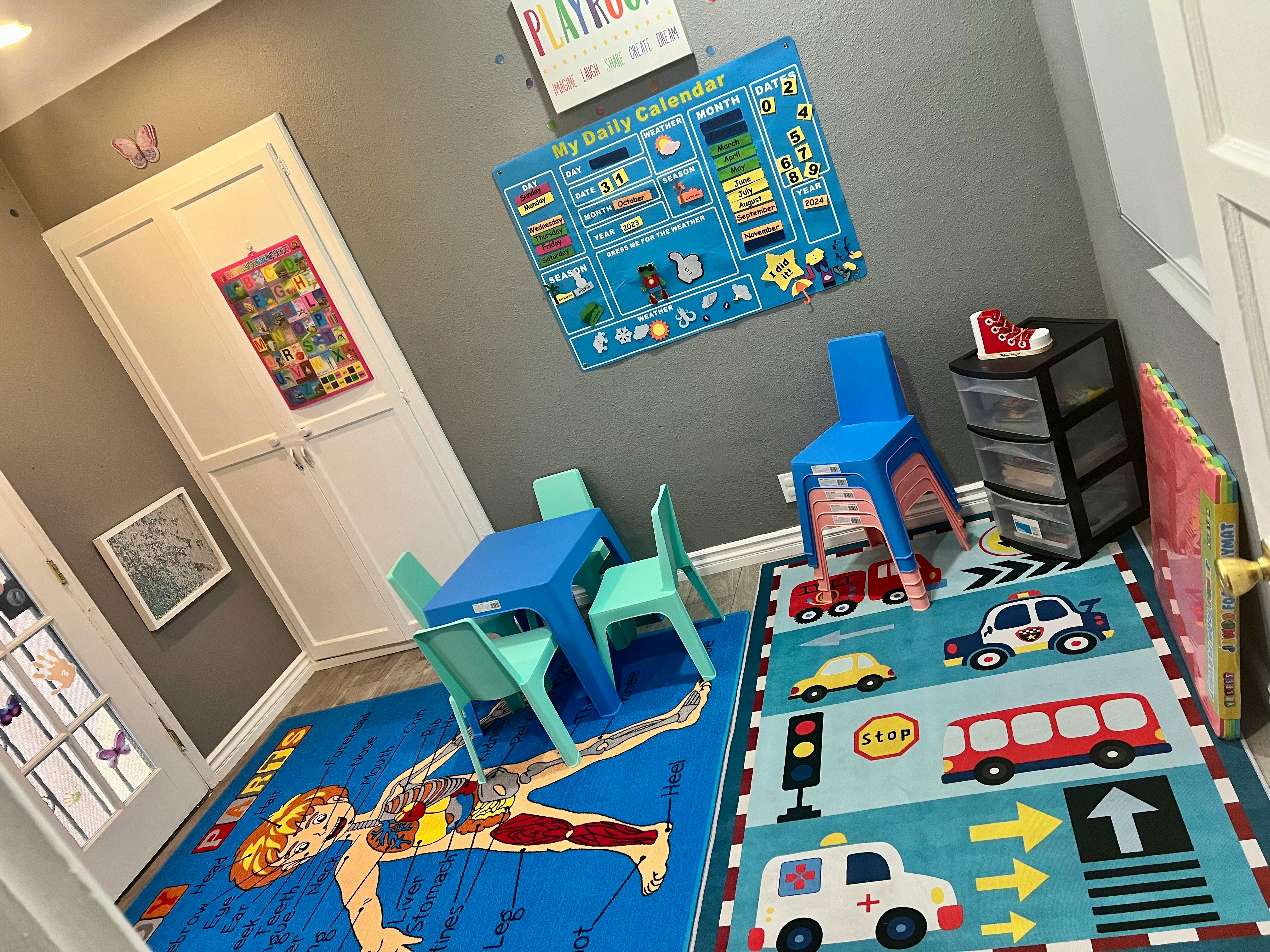 Playroom with small blue table and chairs, colorful rugs, and wall decorations