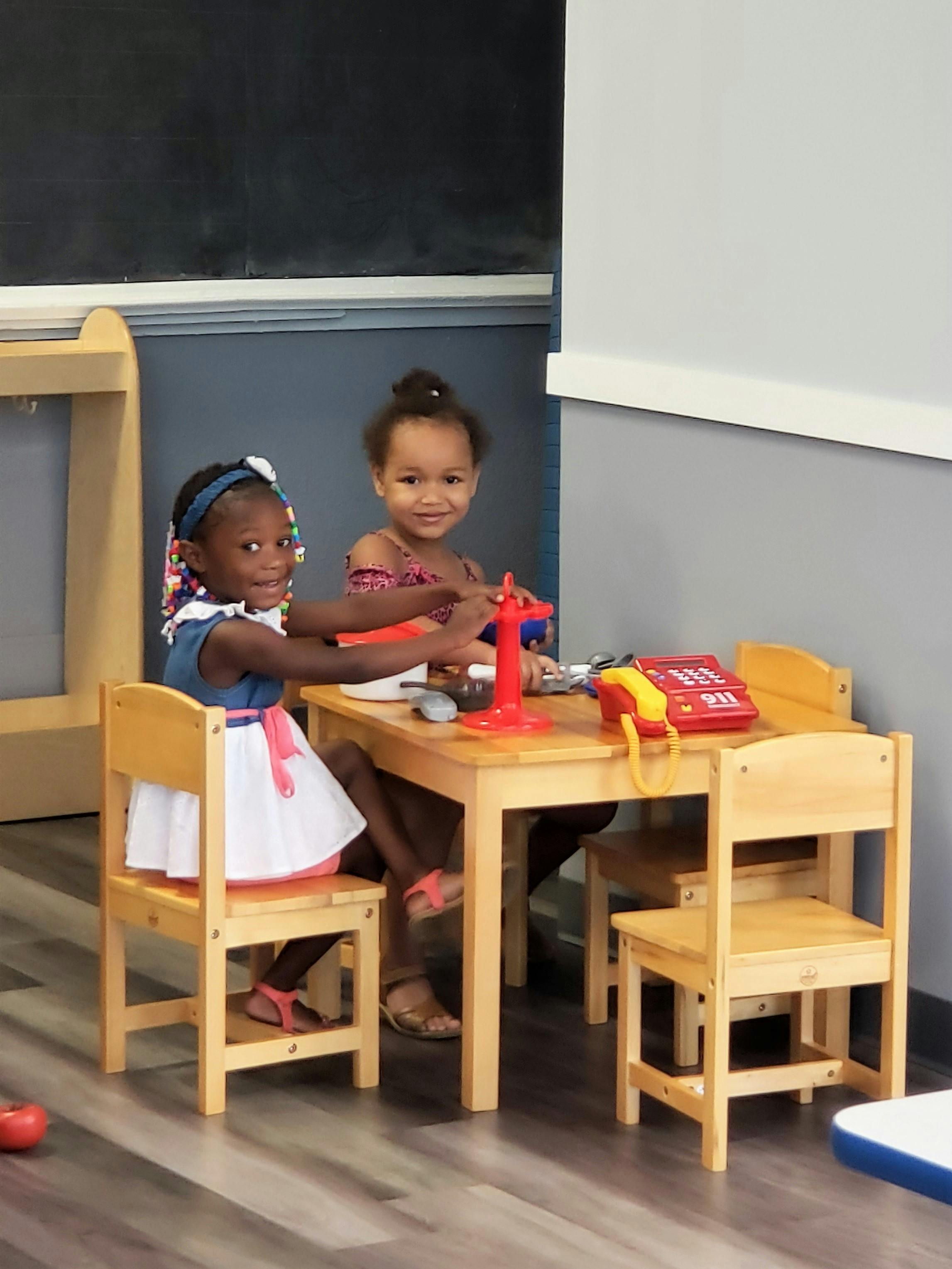 Two children playing at a small table with toys