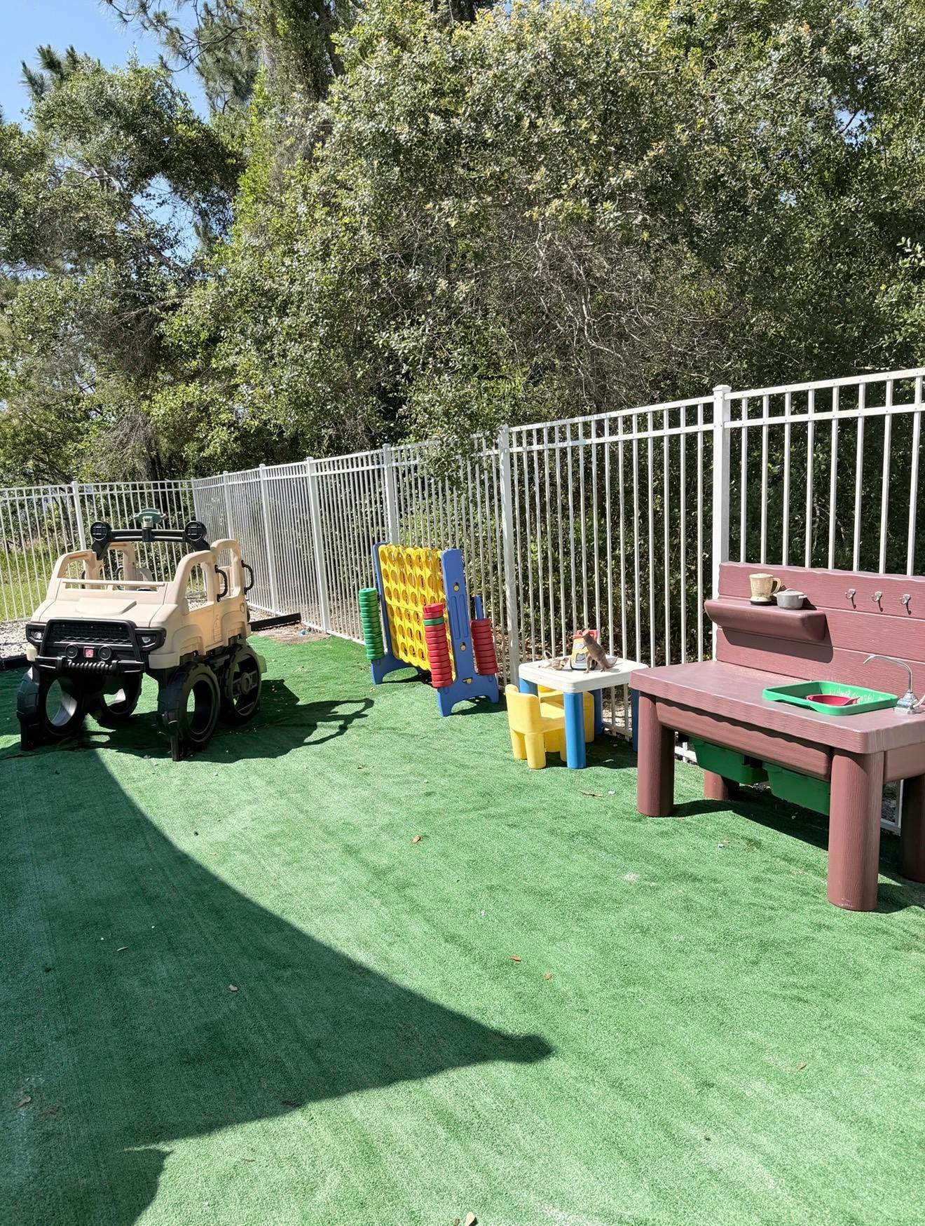 Plastic toy playground equipment on artificial turf in a fenced yard
