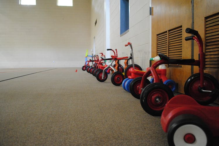 Row of red tricycles and ride-on toys in a room