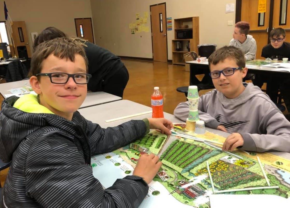 Two children at a table with a large map or game board