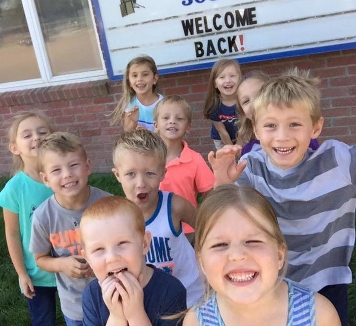 Group of children smiling in front of a "Welcome Back!" sign