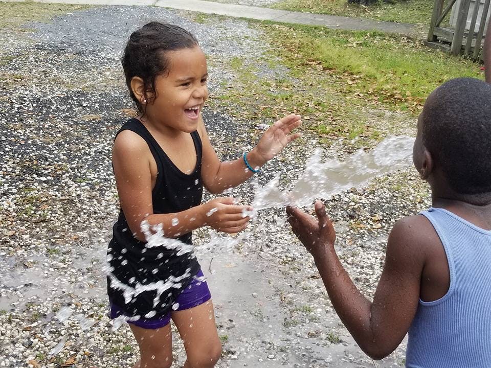 Two children playing with water outdoors
