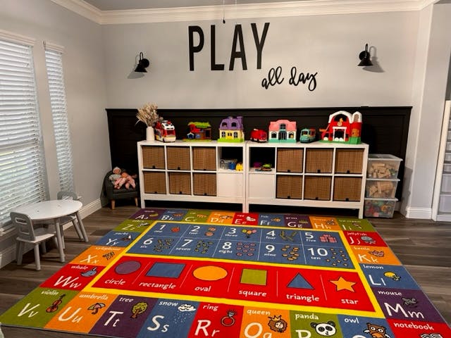 Playroom with a colorful alphabet and numbers rug, toy storage, and wall decor