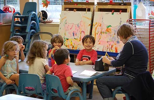Adult and children sitting at a table in a classroom