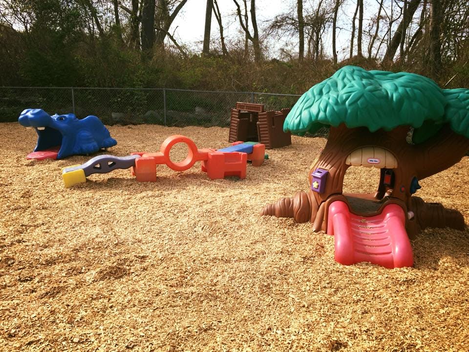 Playground with a treehouse slide and other play equipment on wood chips