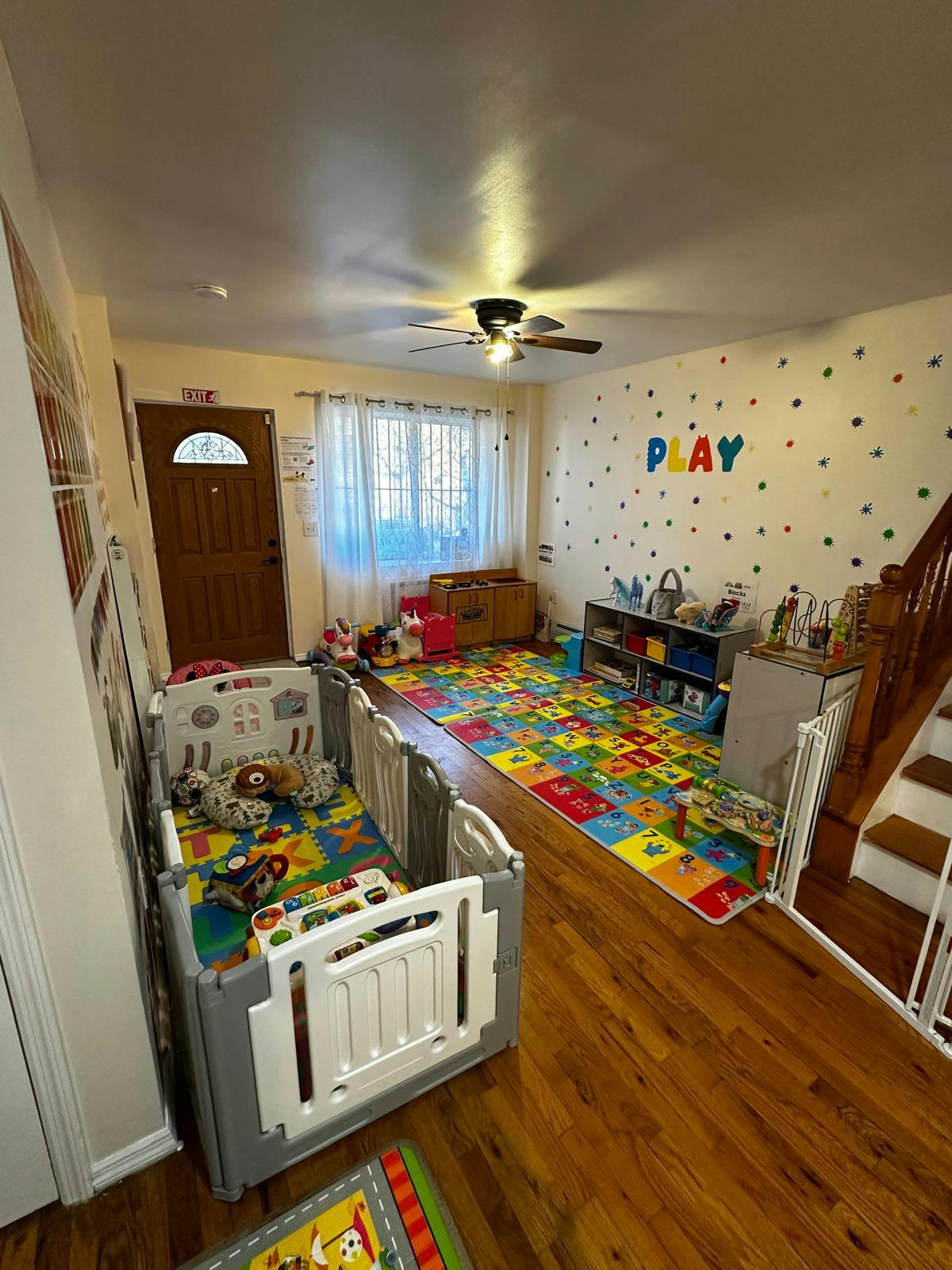 Playroom with a colorful alphabet mat, toys, and a playpen
