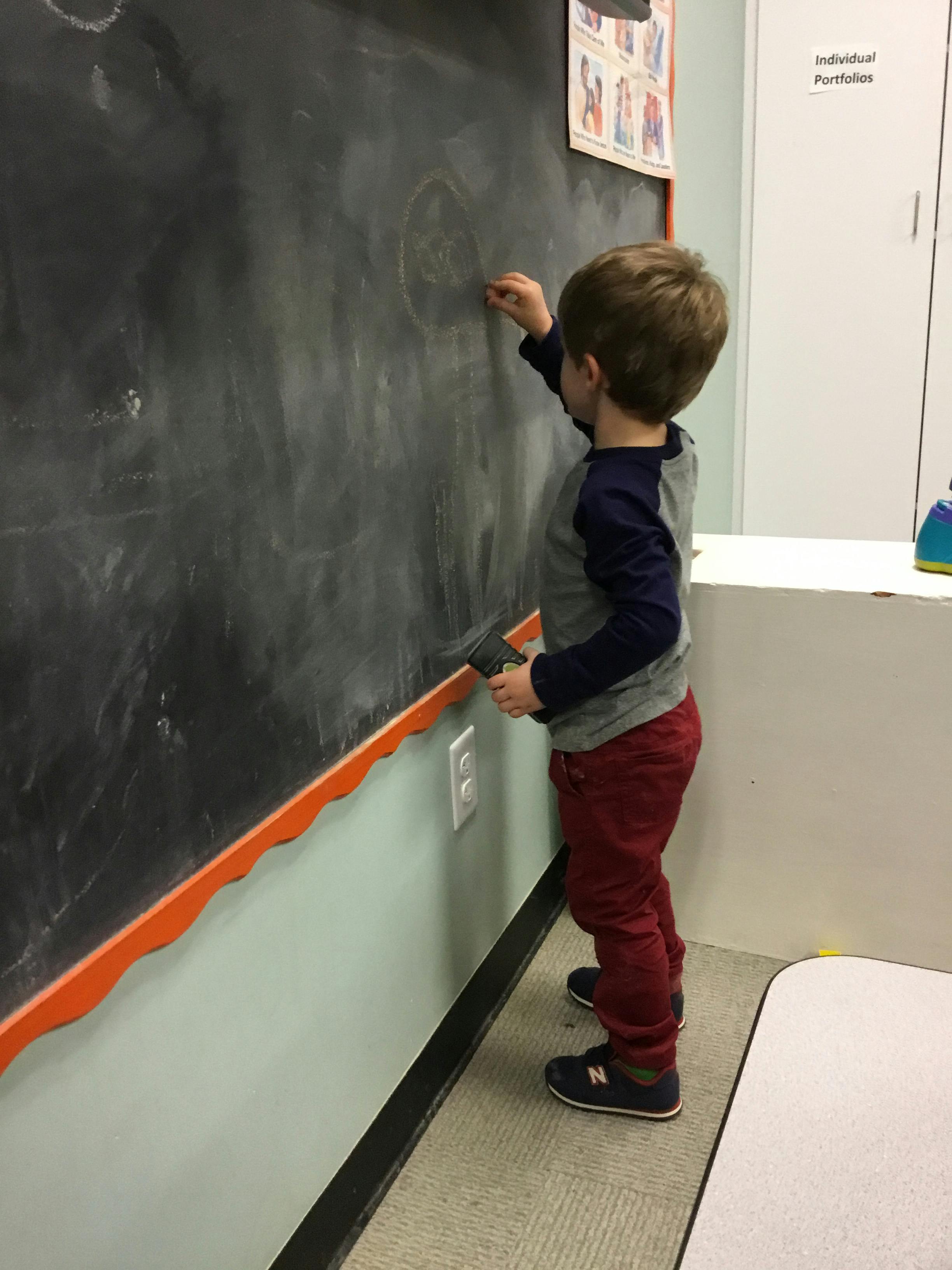 Child drawing on a chalkboard in a classroom