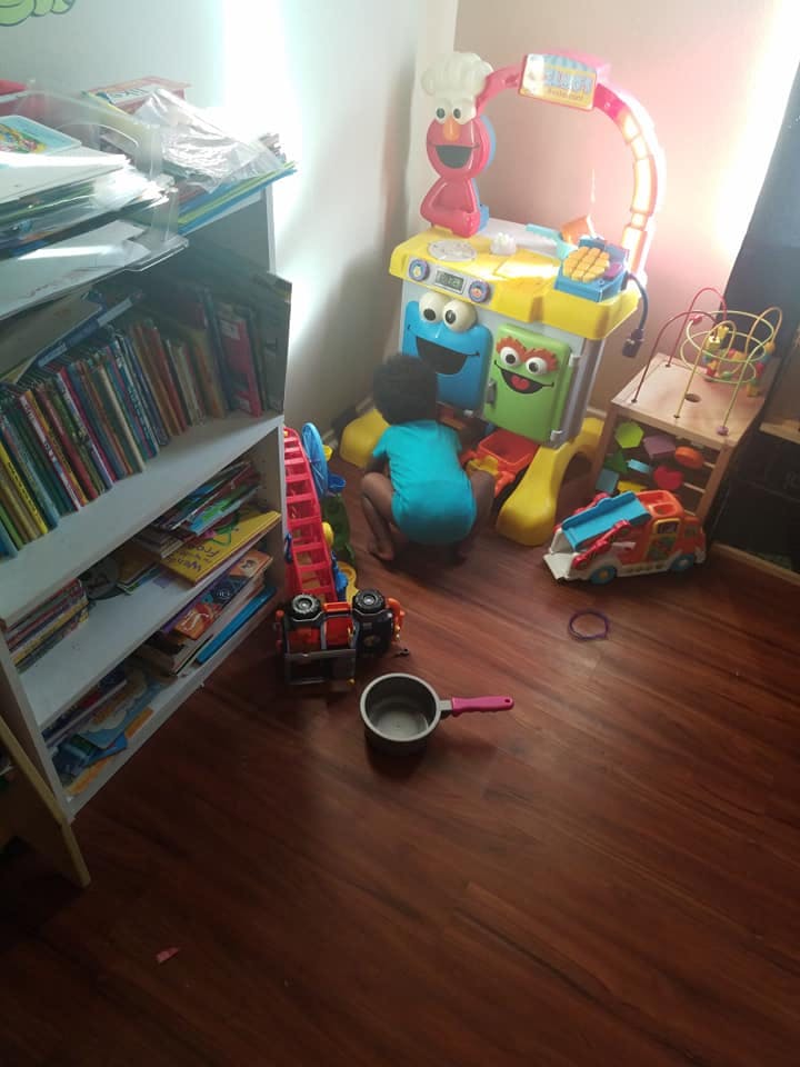 Child playing with toys on a wooden floor next to a bookshelf