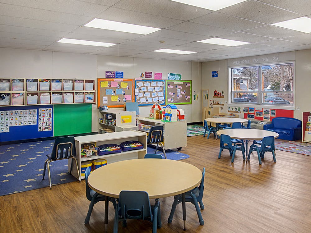 Classroom with small tables and chairs, cubbies, and bulletin boards