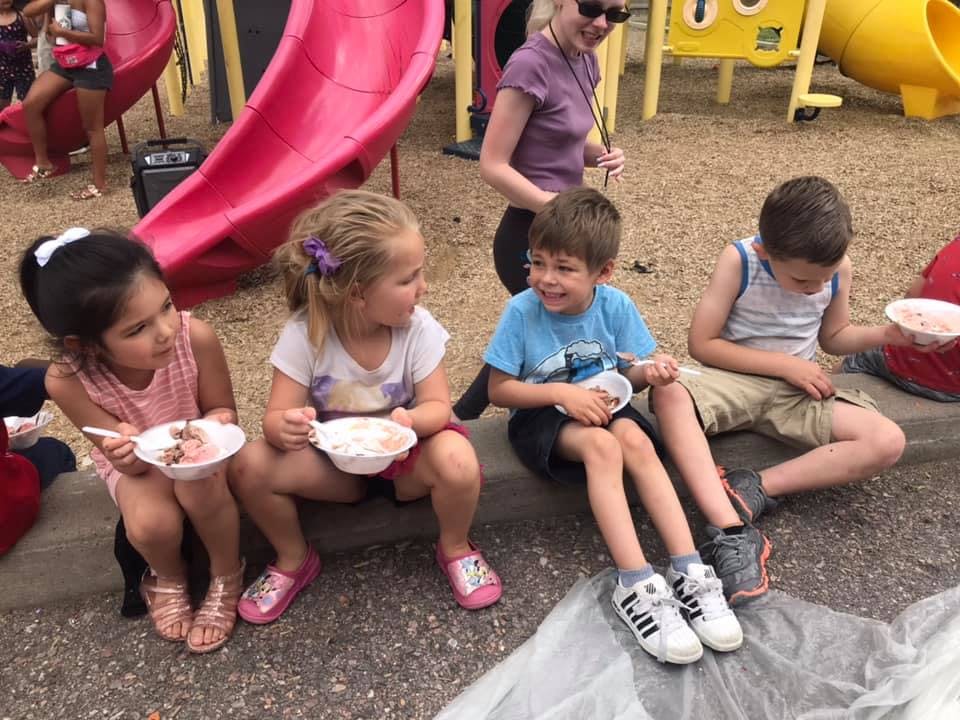 Children sitting and eating from bowls outdoors