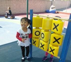 Child standing next to a large tic-tac-toe game