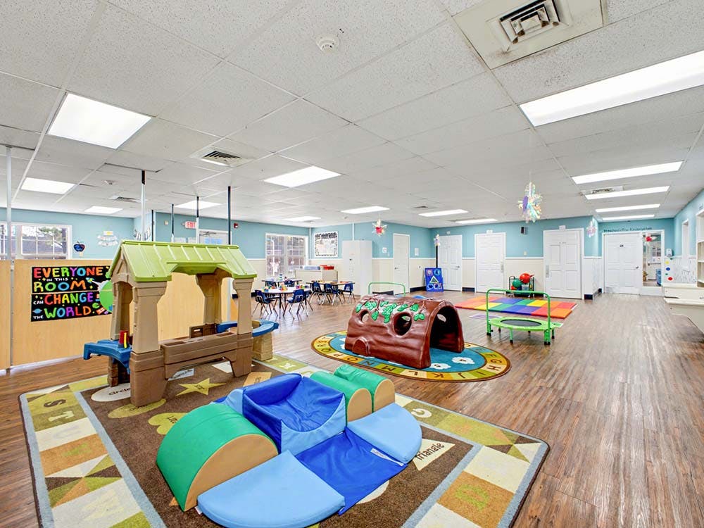 Playroom with soft play shapes, play structures, and small tables