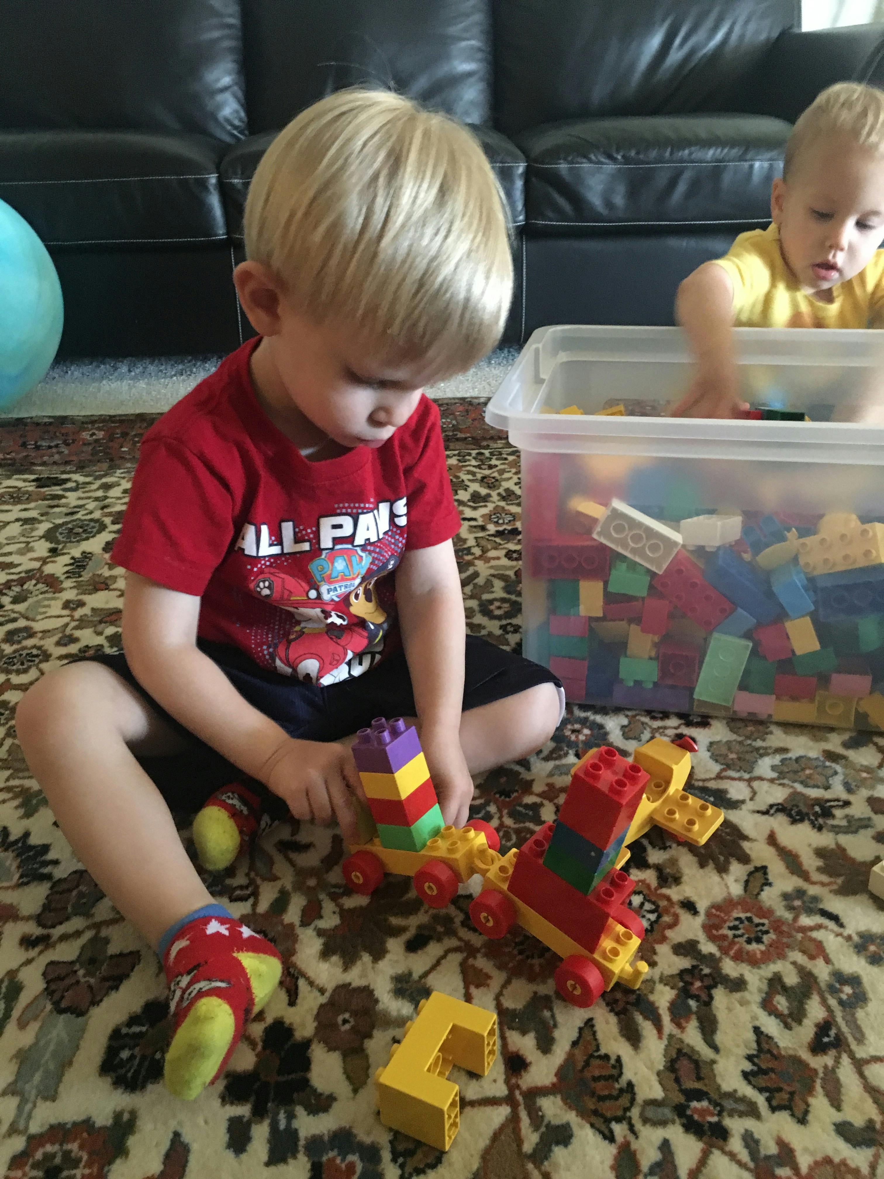 Two children playing with colorful building blocks on a rug