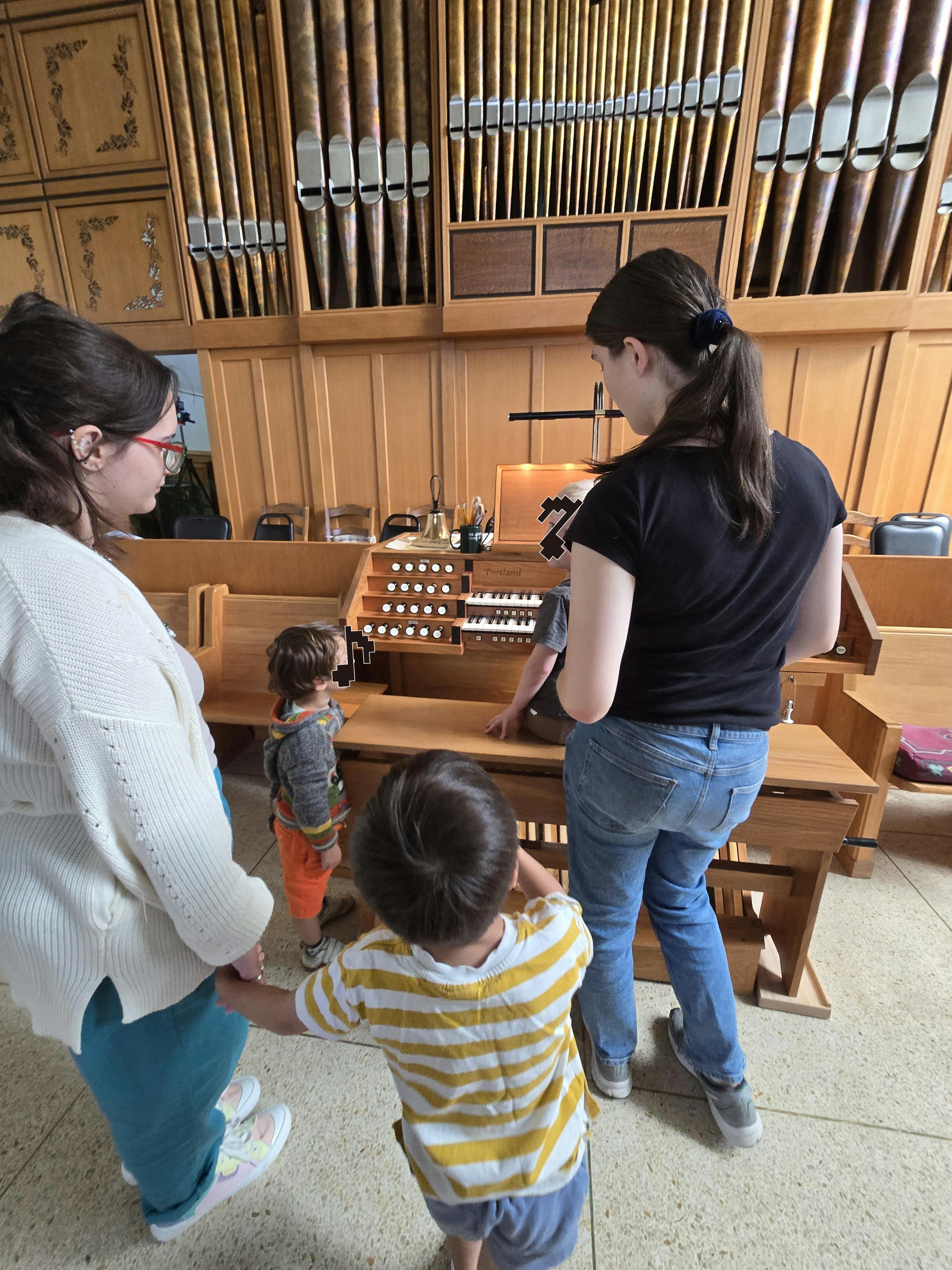 People gathered around a pipe organ in a wooden church interior