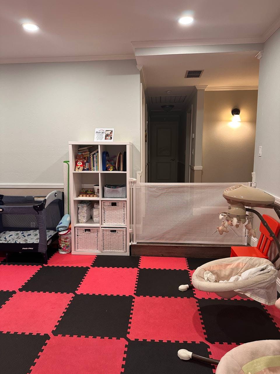Playroom with red and black checkered floor, crib, and baby swing