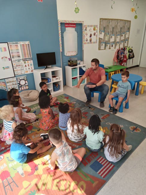 Adult and children sitting on a rug in a classroom