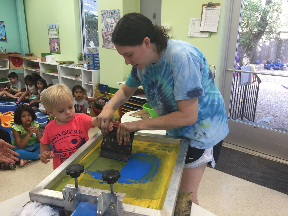 Person and child screen printing in a classroom