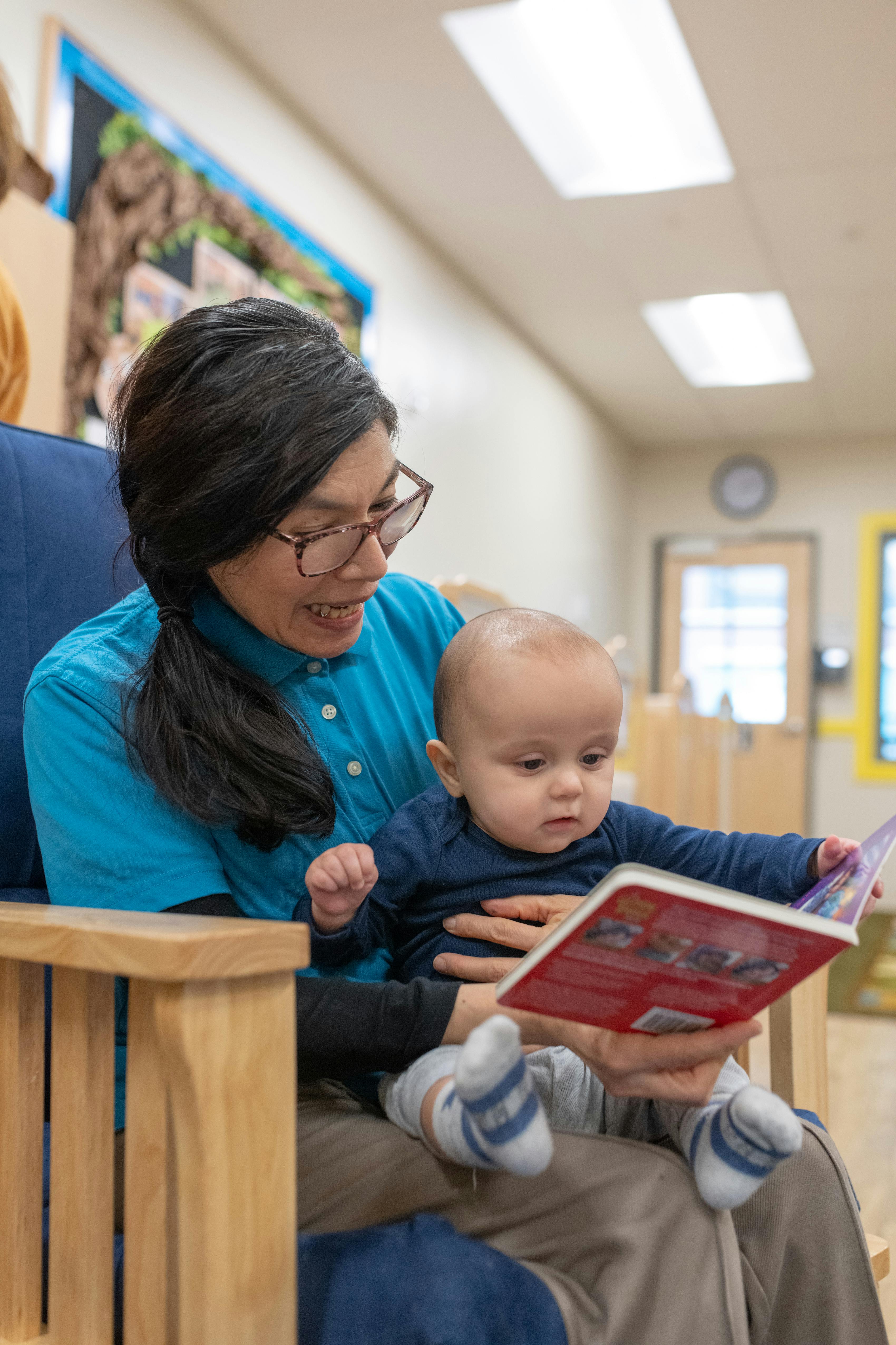 Person in glasses reading a book to a child