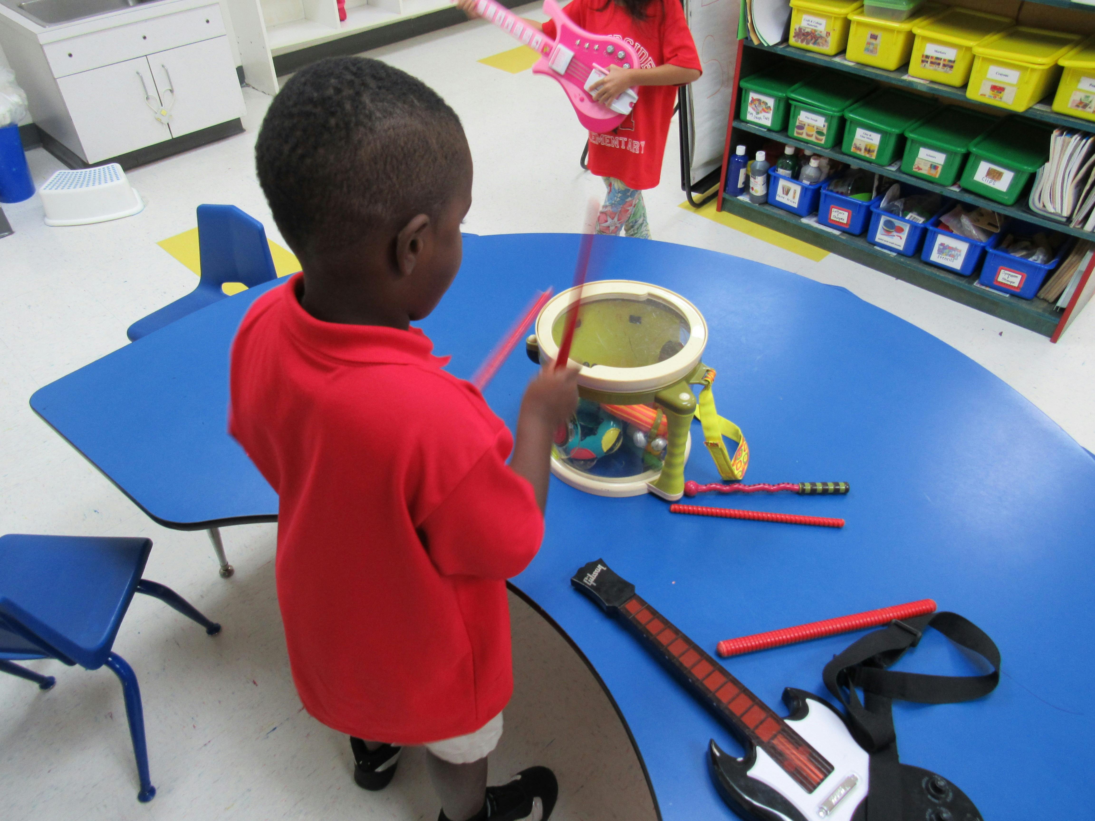 Child playing a drum in a classroom