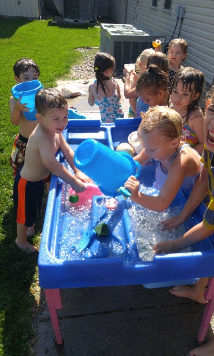 Children playing with water at a blue water table