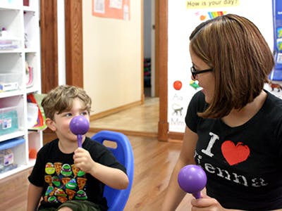 Child and person holding purple shakers in a classroom