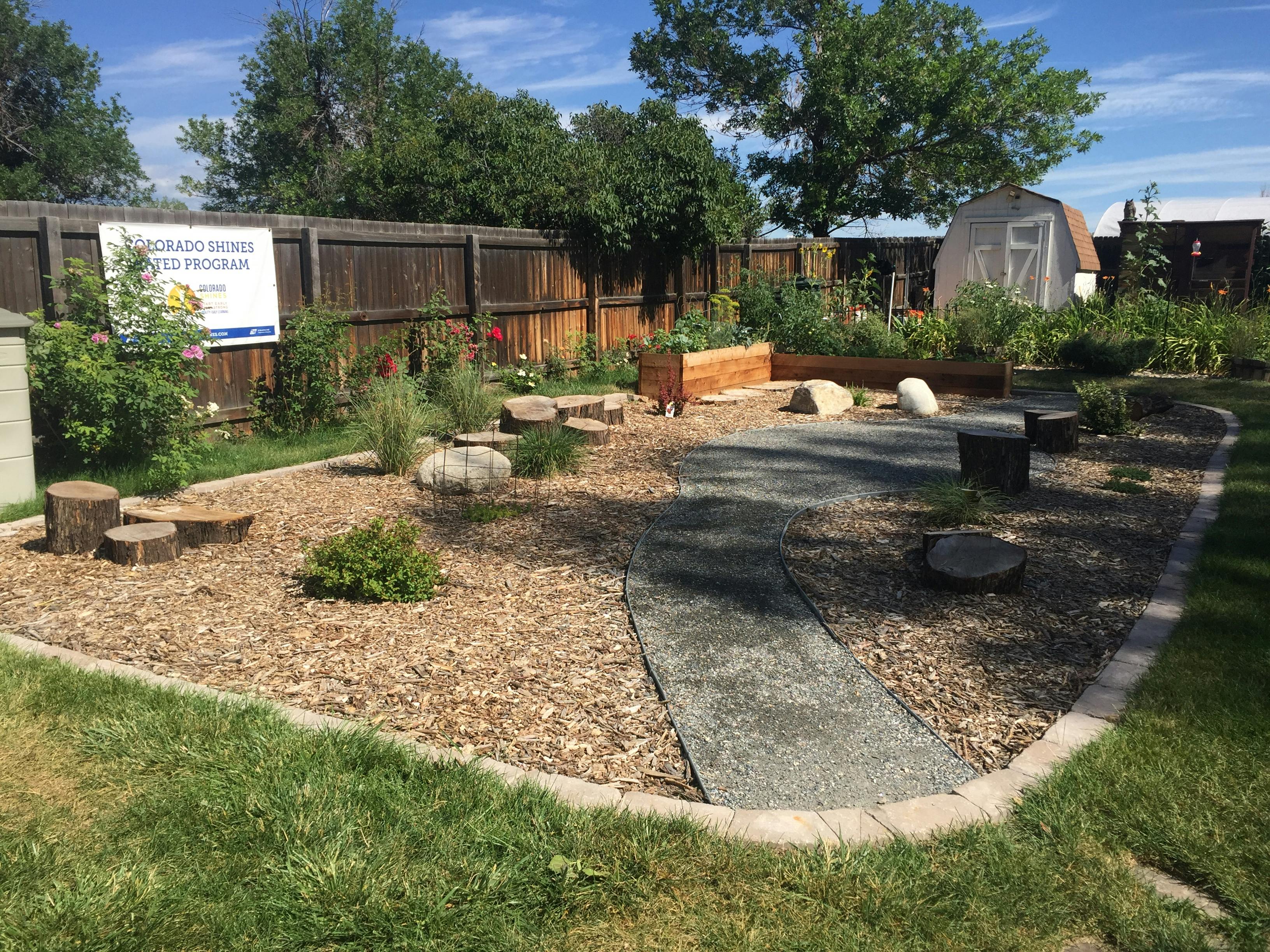Outdoor garden with wood chips, a stone path, and raised garden beds