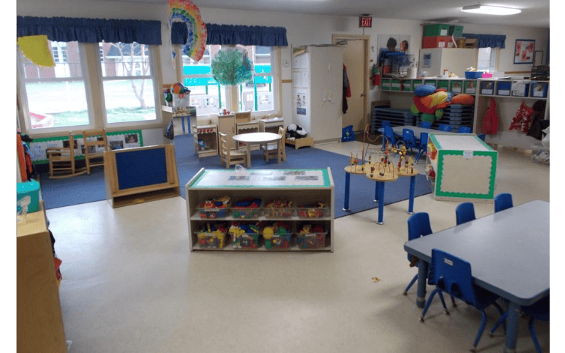 Childcare classroom with small tables, chairs, and activity centers