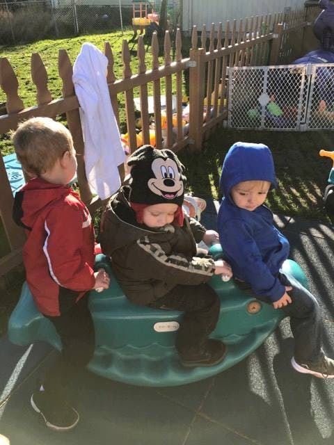 Three children on a green outdoor seesaw