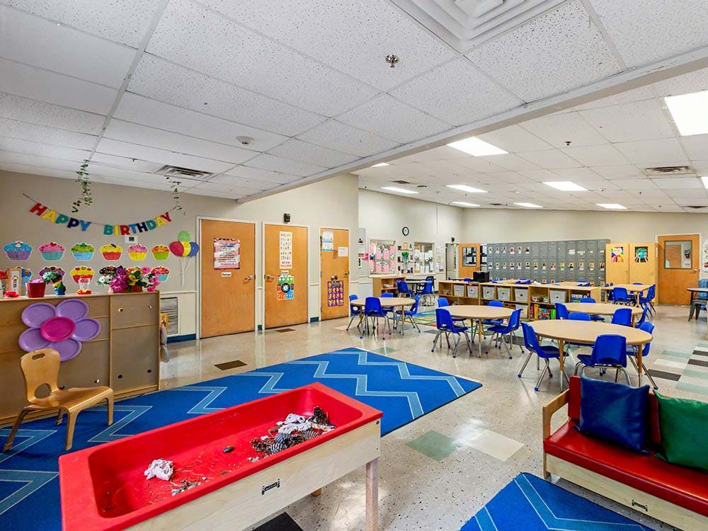Classroom with small tables and chairs, and a happy birthday banner