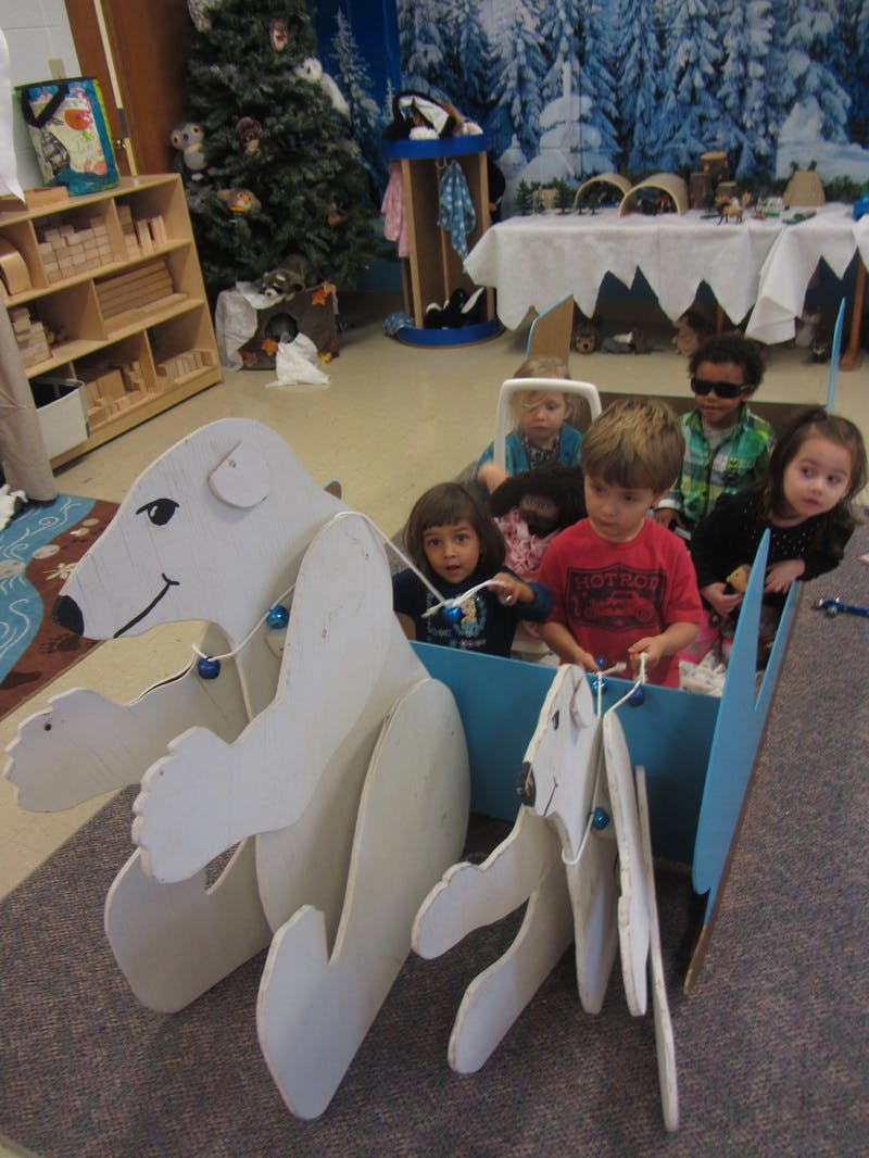 Children in a classroom playing with a polar bear sled