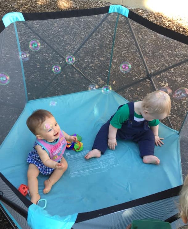 Two children in a playpen with bubbles