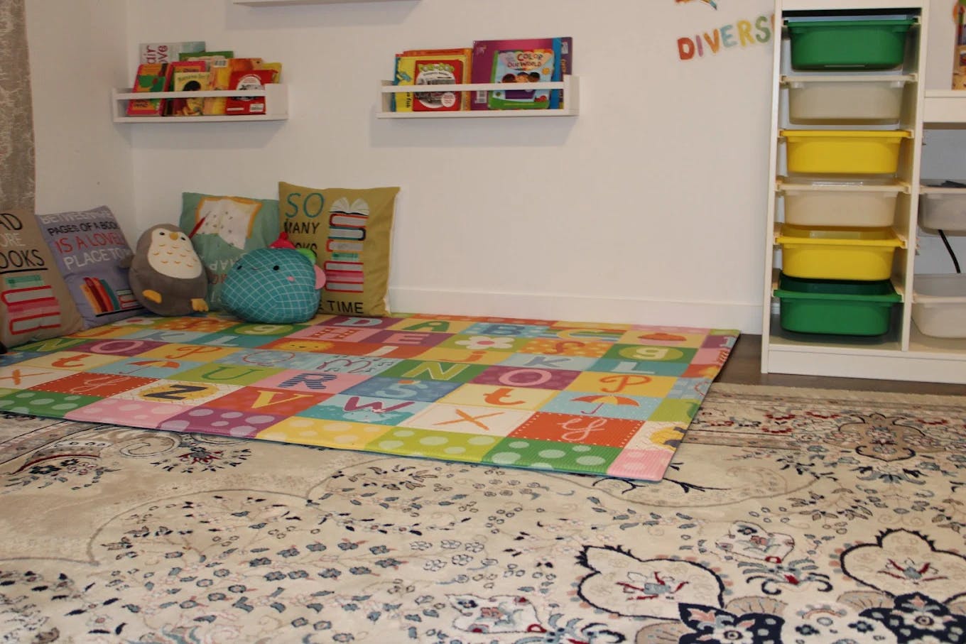Playroom with alphabet mat, pillows, and books on shelves