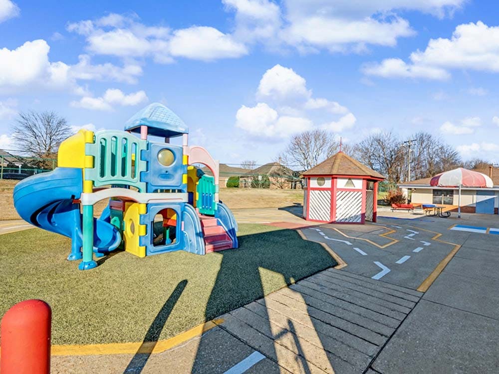 Colorful playground structure with slides and a red and white playhouse