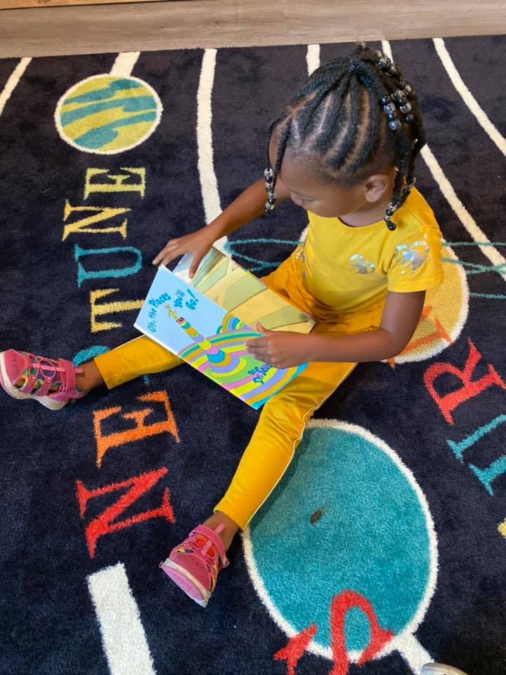 Child sitting on a rug and reading a book