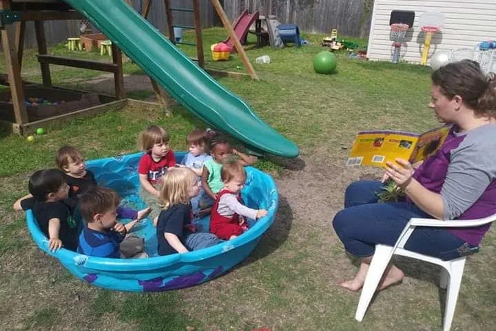 Person reading a book to children in a wading pool