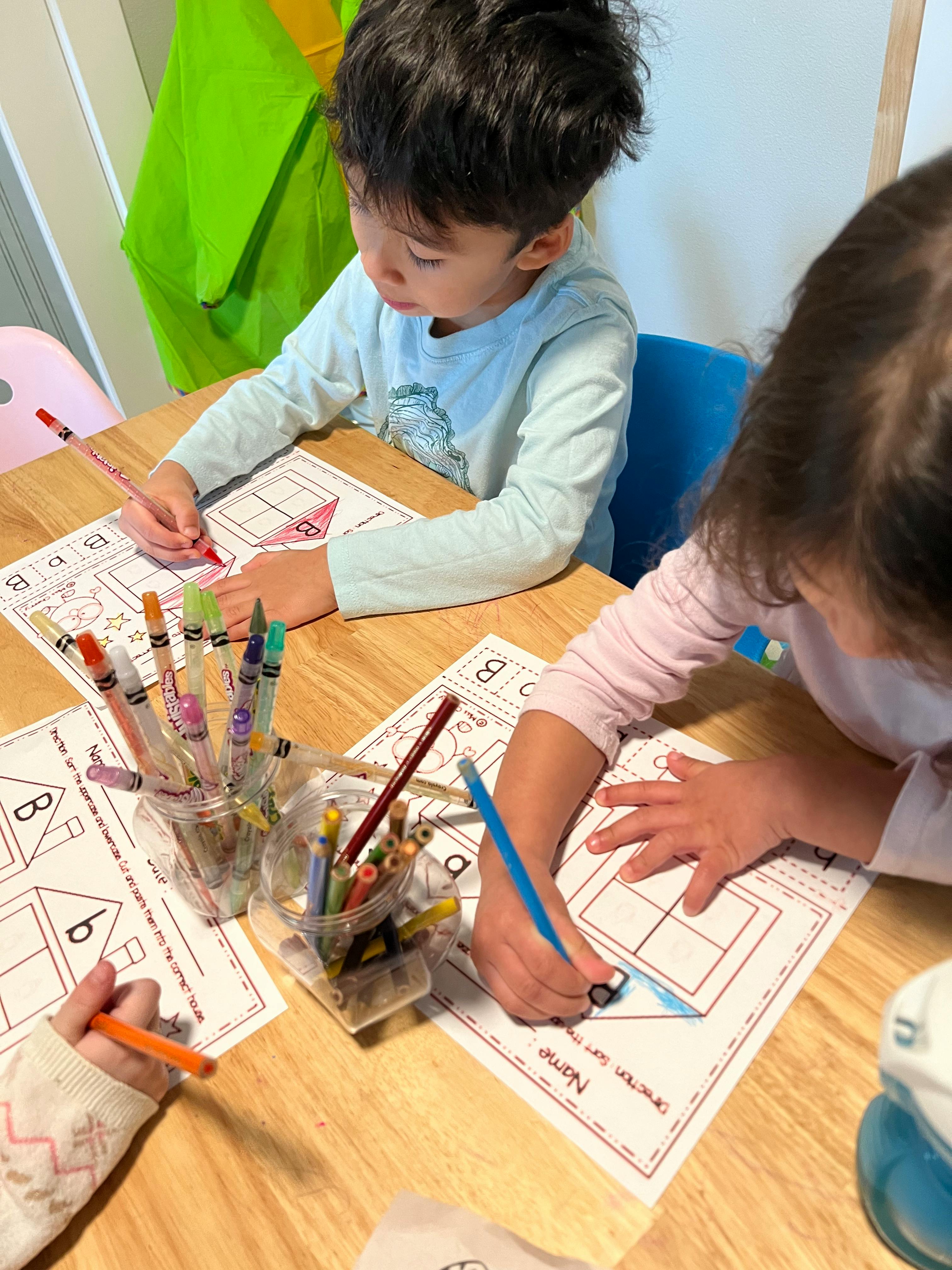 Two children drawing on papers at a table