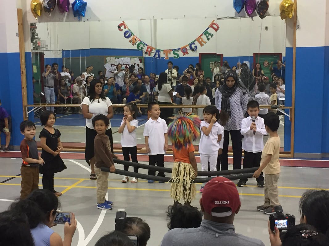 Adults and children on a stage with a "Congratulations Grad" banner