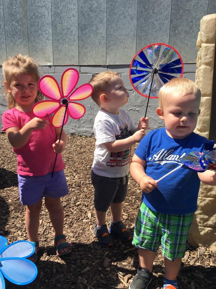 Three children holding pinwheels outdoors