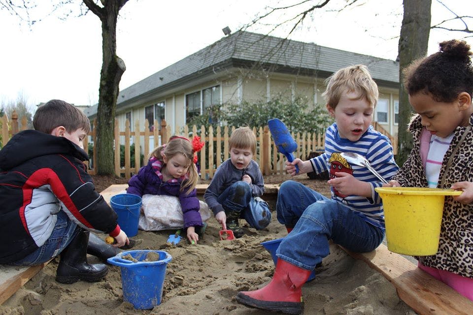 Children playing in a sandbox with shovels and buckets