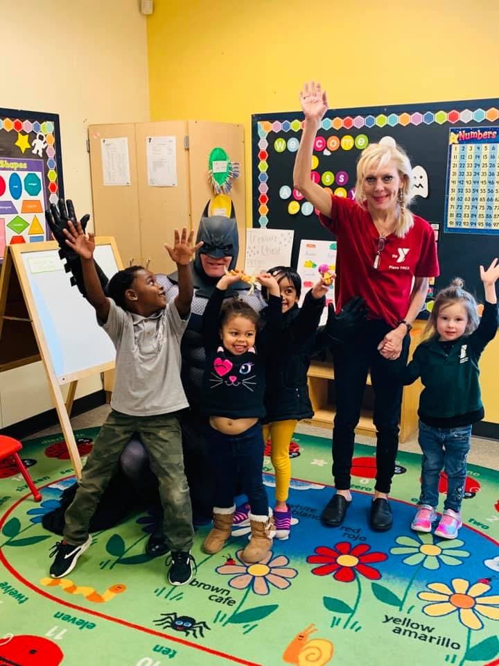 Adults and children in a classroom raising their hands