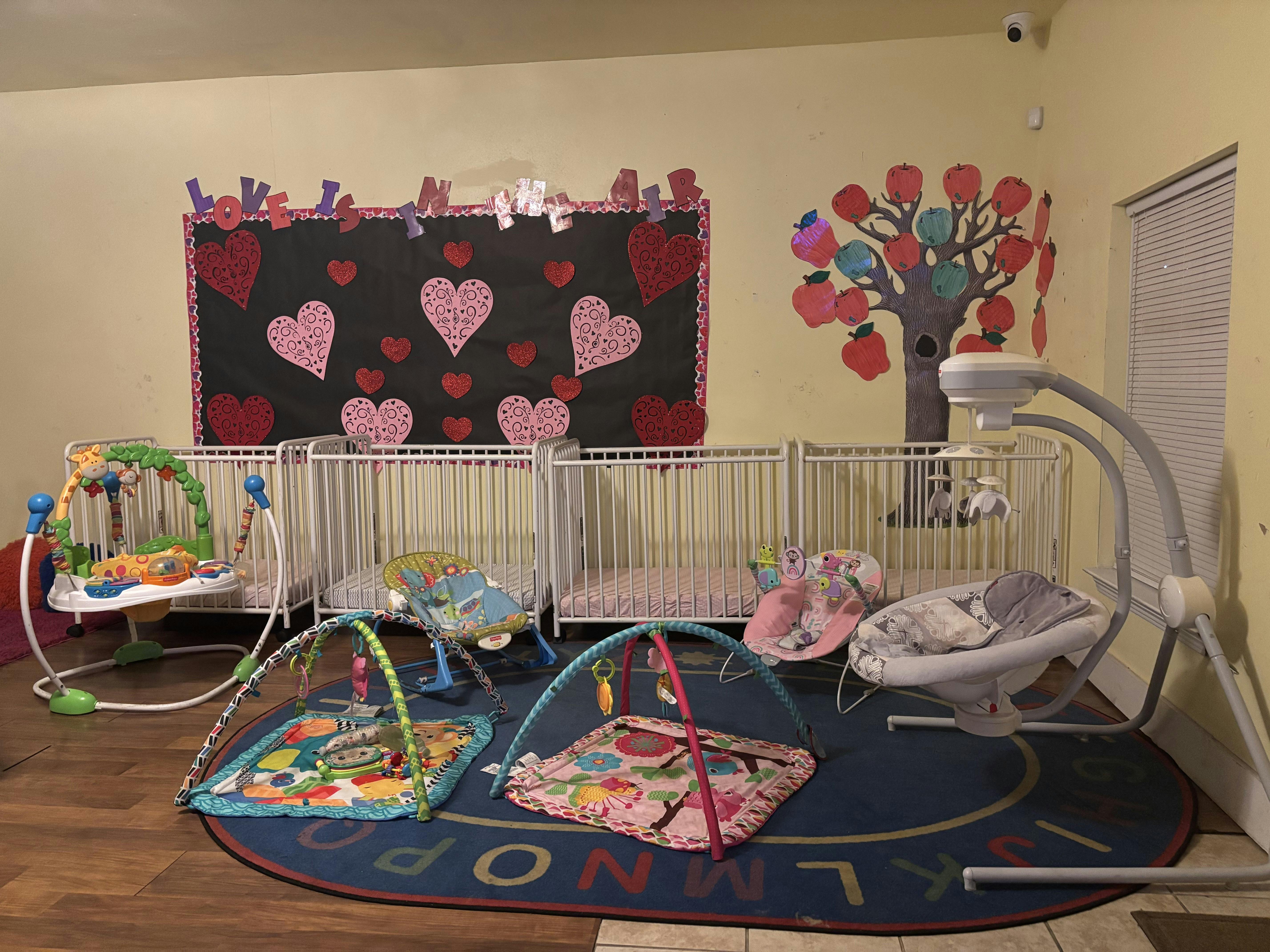 Cribs and infant play equipment in a room with a 