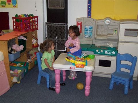 Two children playing at a small table in a classroom