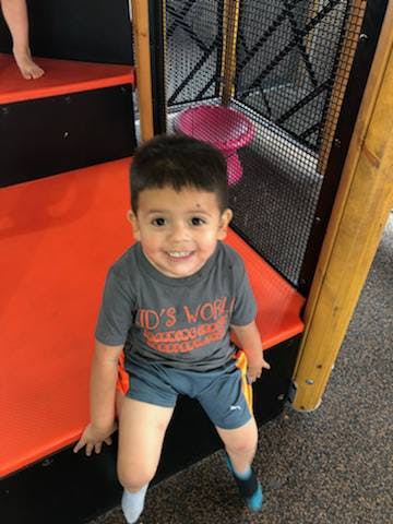 Child sitting on orange steps in an indoor play area