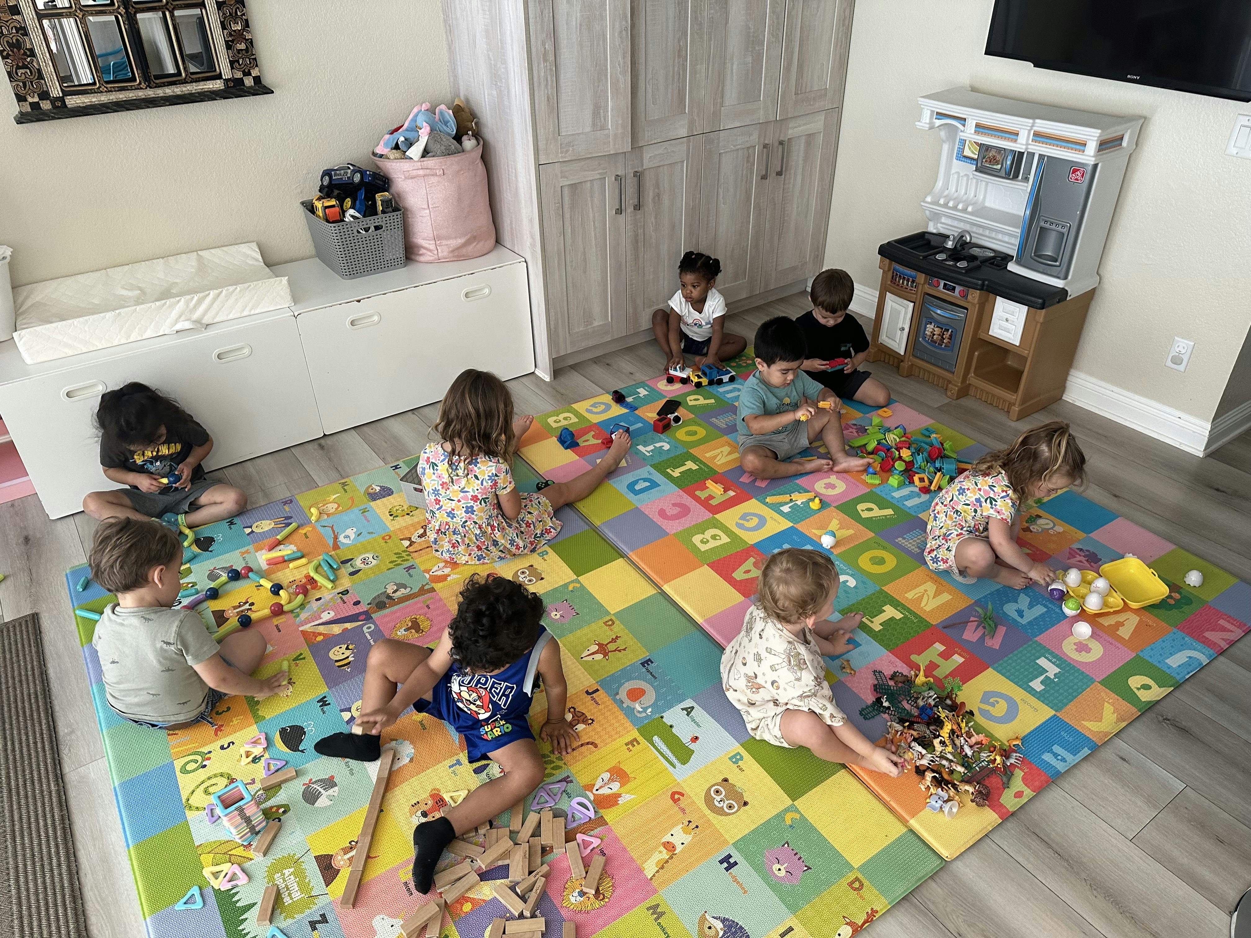 Group of children playing with toys on a colorful alphabet mat