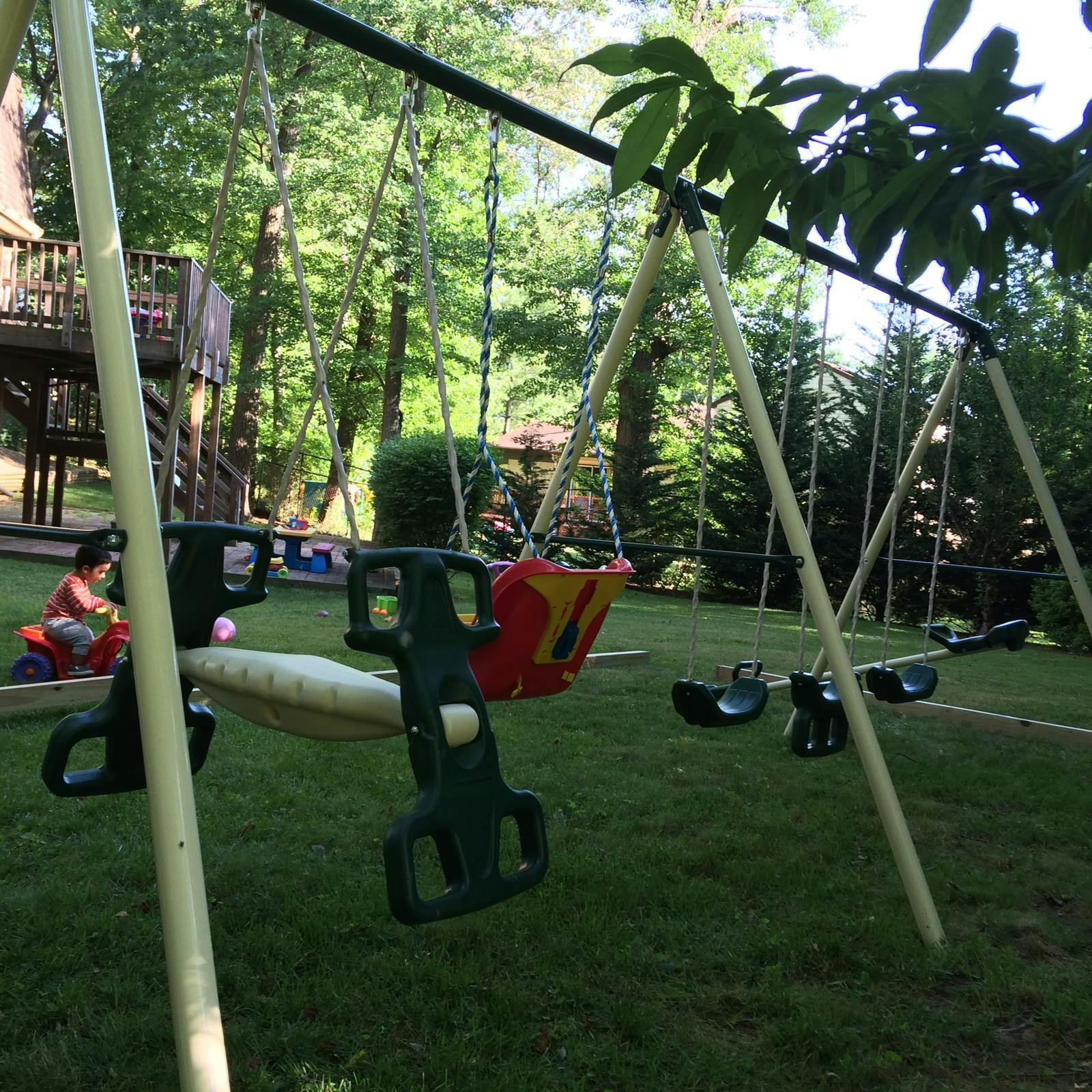 child on a toy ride-on in a backyard with a swing set
