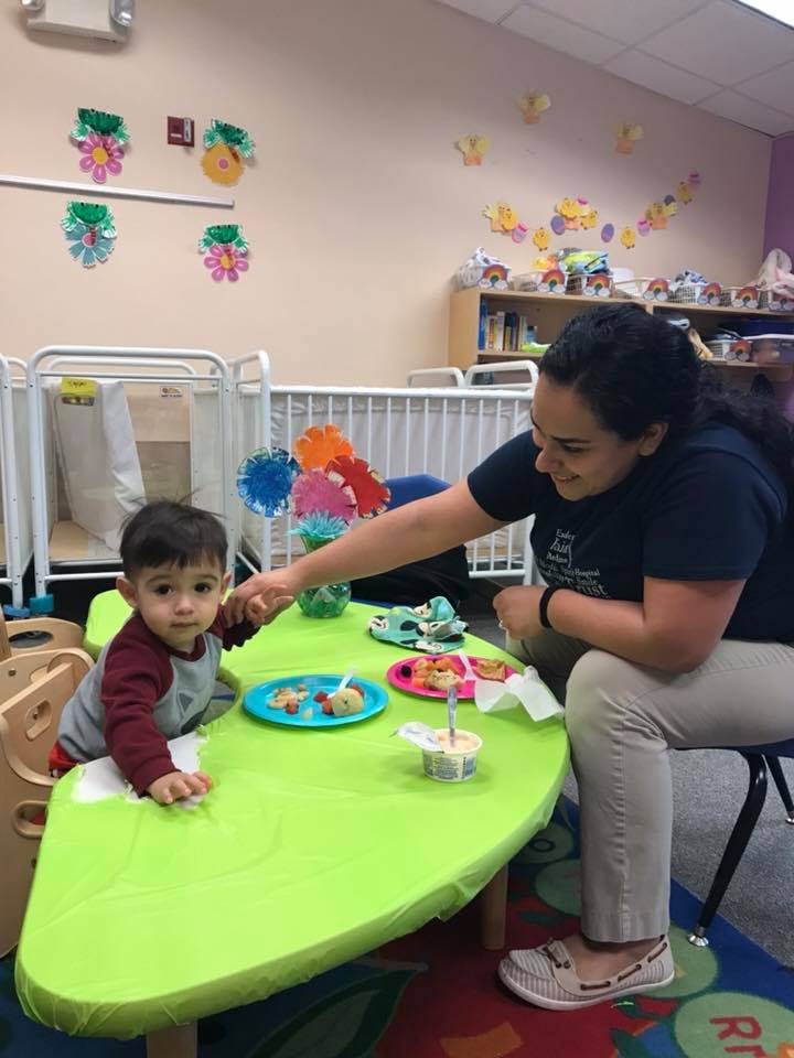 Adult and child at a table with plates of food in a classroom