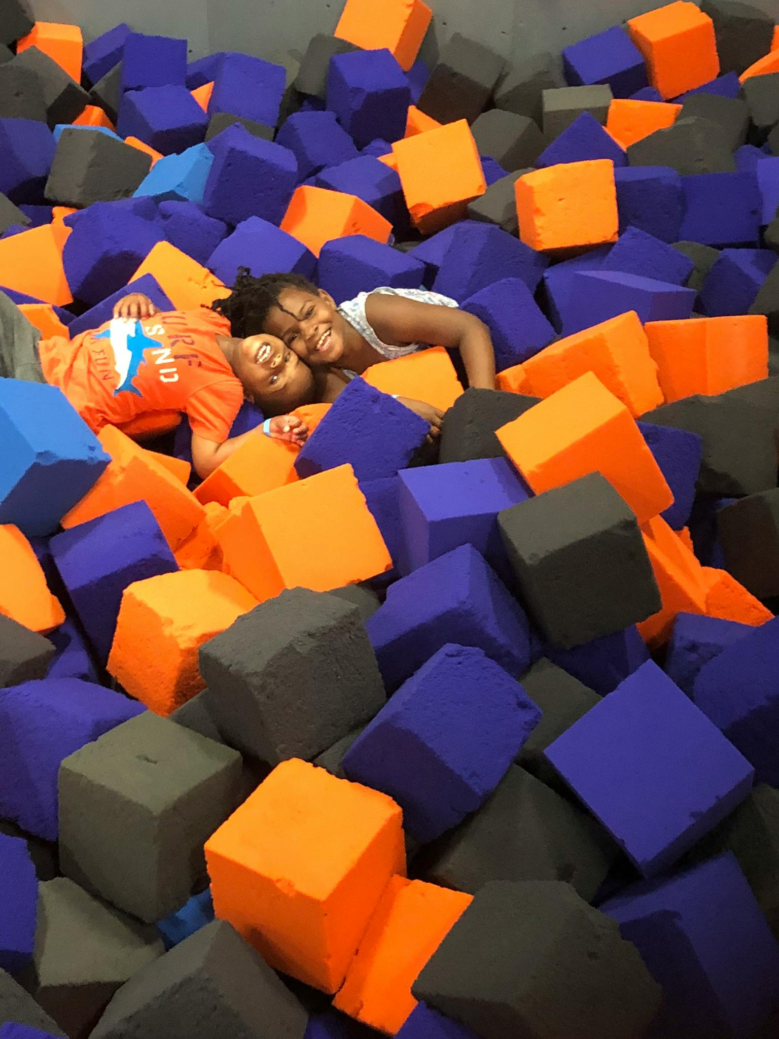Two children lying in a pit of foam blocks