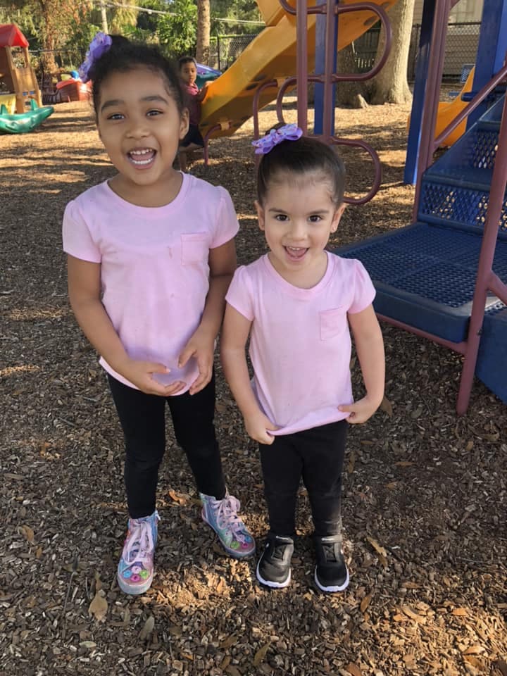 Two children standing on wood chips in a playground