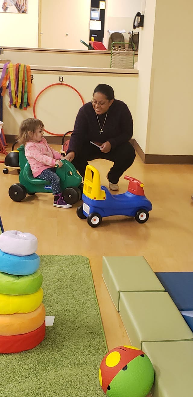Adult and child playing with ride-on toys in a room